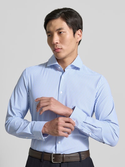 Männermodel trägt Slim Fit Business-Hemd mit Haifischkragen von SEIDENSTICKER, gestreifter Allover-Look, Material-Mix mit Stretch-Anteil, Ganzkörperansicht von vorne. Rückenlänge 78 cm, Schulterbreite 44 cm, Ärmellänge 66 cm, Größe 40.