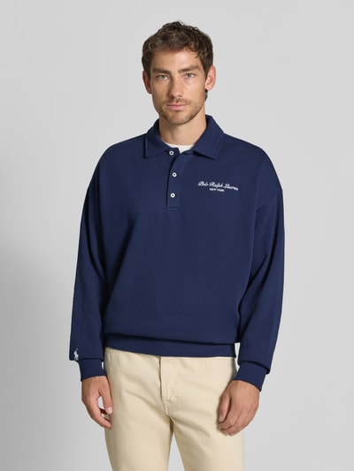 Mężczyzna nosi Relaxed Fit Sweatshirt aus Baumwoll-Mix von Polo Ralph Lauren, granatowy, kremowe spodnie, gładka faktura, Ganzkörperansicht von vorne.
