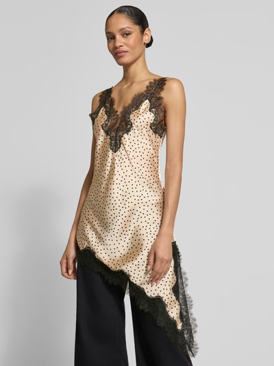 Frauenmodel trägt Top aus Satin in asymmetrischer Form Modell 'SILVER' von Mango, creme mit schwarzen Punkten, Spitzenbesatz, Ganzkörperansicht von vorne.