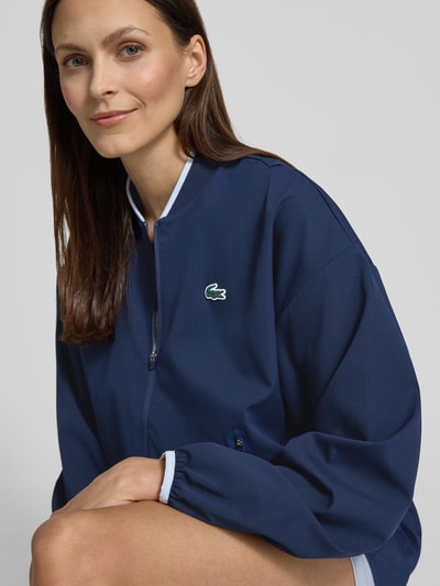 Frauenmodel trägt Regular Fit Trainingsjacke mit Baseball-Kragen von Lacoste Sport in Dunkelblau, unifarben, Label Patch, Nahaufnahme Oberkörper