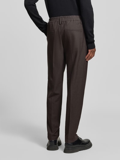 Männermodel trägt Stoffhose mit Bügelfalte Modell 'MARC' von Casual Friday, braun, elastischer Bund, Gesäßleistentaschen, Ganzkörperansicht Rückansicht.