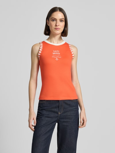 Frauenmodel trägt Slim Fit Top mit Statement-Print von Marc Cain, in Orange mit weißen Details, Baumwoll-Mix, Rundhalsausschnitt, Rückenlänge 50 cm bei Größe 36, Ganzkörperansicht von vorne.