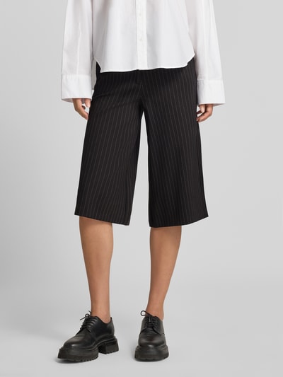 Frauenmodel trägt Regular Fit Culotte mit Bundfalten Modell 'SC-GILL 3' von Soyaconcept, schwarz mit weißen Nadelstreifen, 3/4-Länge, Webware, Eingrifftaschen, Nahaufnahme Unterkörper, KI-modifiziertes Bild.