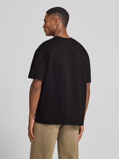 Męski model nosi T-Shirt mit Rundhalsausschnitt Modell 'Carl' von Les Deux, czarny, bawełna, prosty krój, widok całej sylwetki z tyłu.