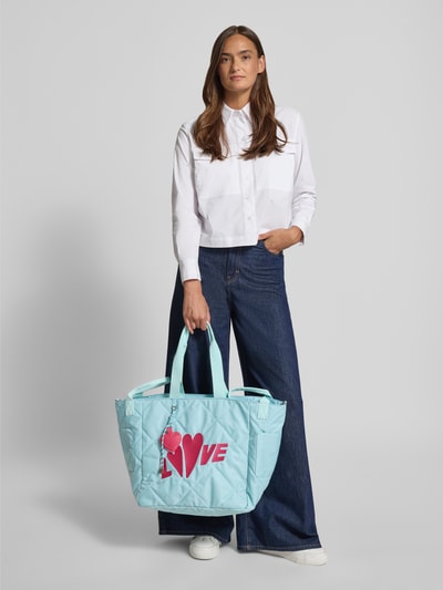 Frauenmodel trägt Shopper mit Stitching Modell 'Love' von miss goodlife in Hellblau mit Steppnähten, Magnetverschluss und Henkel, Ganzkörperansicht von vorne.