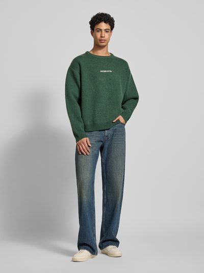 Männermodel trägt Strickpullover mit gerippten Abschlüssen von ANOTHER COTTON LAB im Material-Mix, lockerer Schnitt, Ganzkörperansicht von vorne.