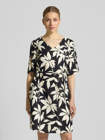Frauenmodel trägt Relaxed Fix Freizeitkleid aus Viskose-Mix von s.Oliver RED LABEL, Optik:Allover-Muster, Mini-Länge, V-Ausschnitt, Taillengürtel, Kurzarm, Materialverarbeitung: Crinkle, Farben Schwarz und Creme, Ganzkörperansicht von vorne.