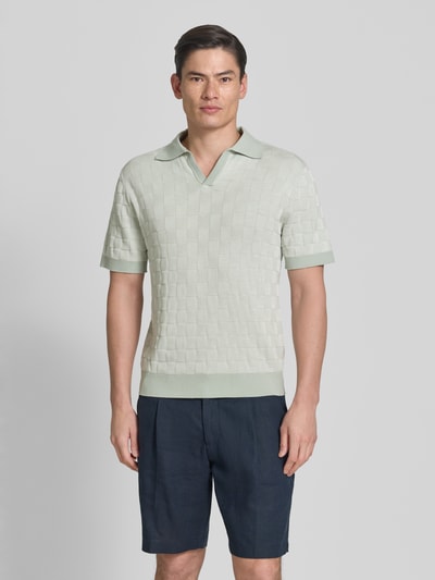 Männermodel trägt Relaxed Fit Poloshirt aus reiner Baumwolle Modell 'MILAS' von SELECTED HOMME, mehrfarbig, Gitterkaro-Strick, Ganzkörperansicht von vorne.
