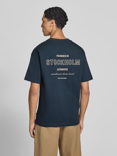 Männermodel trägt Relaxed Fit T-Shirt aus reiner Baumwolle von Marc O'Polo in Dunkelblau mit weißem Aufdruck, Ganzkörperansicht Rückansicht, Herren Oversized Shirt von Marc O'Polo DENIM.