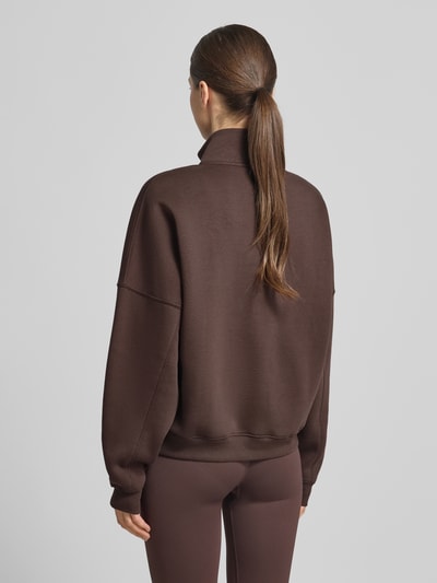 Frauenmodel trägt Sweatshirt mit Stehkragen und Reißverschluss von aim'n, dunkelbrauner Baumwoll-Mix, Relaxed Fit, Ganzkörperansicht Rückansicht.