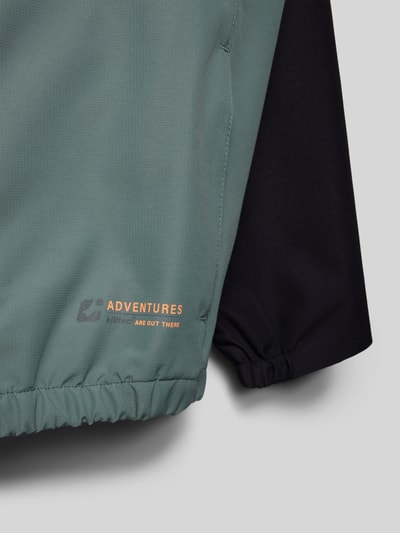 Produktfoto, Regular Fit Jacke mit Logo-Detail von Killtec in Grün mit schwarzem Ärmel, strukturierte Oberfläche, Detailaufnahme des Saums mit Logoprint, Reißverschluss und elastischem Bund, Jacke für Kinder mit Napoleontaschen und Eingrifftaschen.