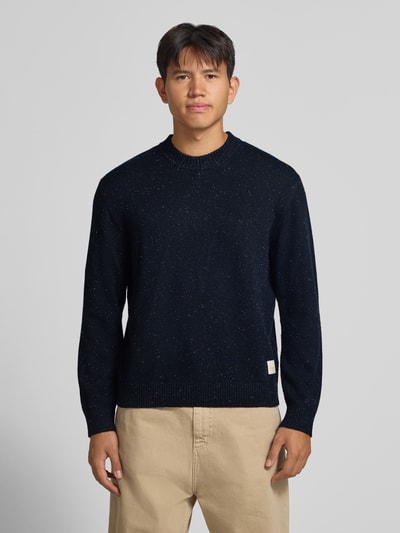Männermodel trägt Regular Fit Strickpullover mit Rundhalsausschnitt von JACK & JONES, dunkle Farbe, gerippte Abschlüsse, Ganzkörperansicht von vorne.