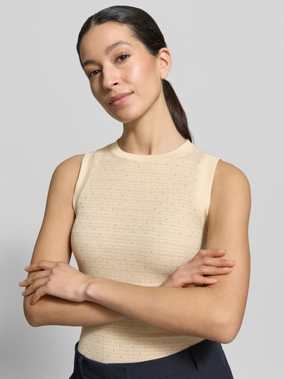 Kobiece modelka nosi Top mit Ziersteinbesatz und Rundhalsausschnitt od GUESS, mieszanka materiałów z dodatkiem streczu, krój slim fit, model 'FRANCINE', okrągły dekolt, ozdobne kamienie i detal z logo, długość tyłu w rozmiarze S: 52 cm, jasny kolor, gładka tekstura, zbliżenie na górną część ciała.