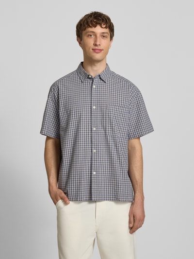 Männermodel trägt Loose Fit Freizeithemd aus reiner Baumwolle Modell 'DAVES' von Only & Sons mit kariertem Allover-Muster, Ganzkörperansicht von vorne.
