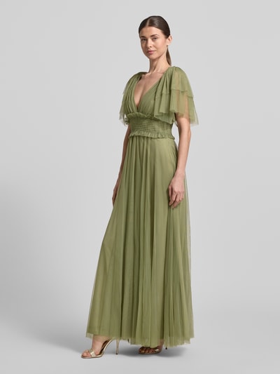 Frauenmodel trägt Maxikleid mit V-Ausschnitt und Taillenband von LACE & BEADS aus olivgrünem Tüll, taillierter Schnitt, Ganzkörperansicht von vorne.