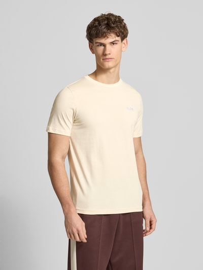Männermodel trägt T-Shirt aus reiner Baumwolle von PUMA PERFORMANCE in Beige mit Rundhalsausschnitt, gerader Schnitt, Ganzkörperansicht von vorne.