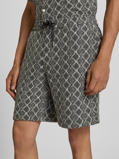 Männermodel trägt Shorts im Allover-Look mit Kordelzug Modell 'CARLOS' von Redefined Rebel aus Reine Baumwolle, Nahaufnahme Oberschenkel. Regular-Fit, Elastischer Bund, Bundweite bei Größe M: 40 cm, Innenbeinlänge bei Größe M: 19 cm.