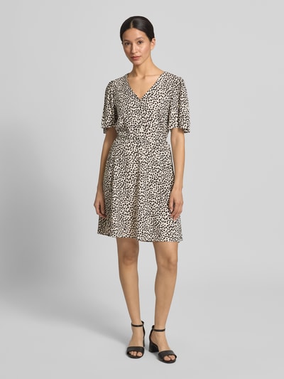 Frauenmodel trägt Minikleid aus Viskose mit kurzer Knopfleiste Modell 'GRACE' von Vila, cremefarben mit schwarzem Tupfenmuster, Taillierter Schnitt, V-Ausschnitt, Bindegürtel, Rückenlänge 87 cm, Brustweite 46 cm, Ärmellänge 25 cm, Ganzkörperansicht von vorne.