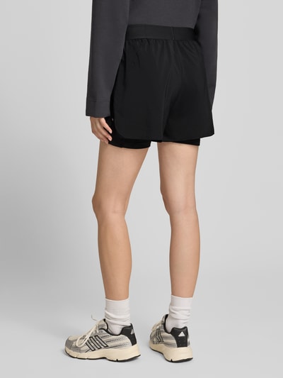 Frauenmodel trägt schwarze Regular Fit Sportshorts mit Logo-Details Modell 'Run Ess 21 S' von adidas aus adidas Training, Ganzkörperansicht Rückansicht.
