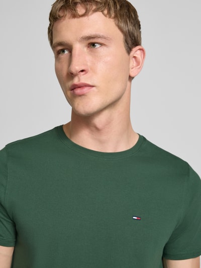 Männermodel trägt Regular Fit T-Shirt aus reiner Baumwolle von Tommy Jeans in Optik: Unifarben, Logo-Stitching, Nahaufnahme Oberkörper.