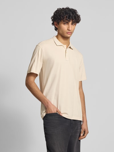 Männermodel trägt Regular Fit Poloshirt aus reiner Baumwolle Modell 'Core' von G-Star Raw in Beige, Polokragen, Label-Detail, Ganzkörperansicht von vorne.