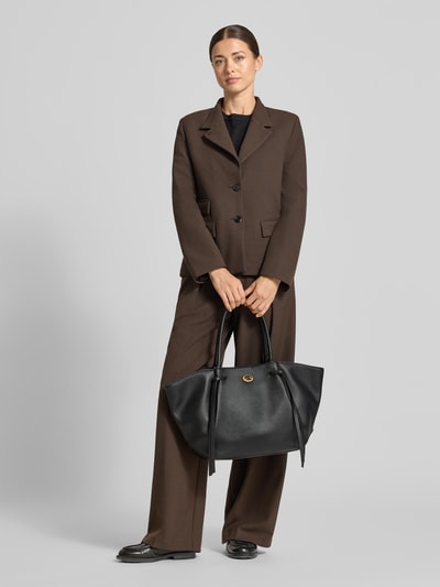 Frauenmodel trägt Tote Bag in Leder-Optik Modell 'ALLEGRA' von GUESS, Schwarz, Logo-Detail, Geteiltes Hauptfach, Ganzkörperansicht von vorne.