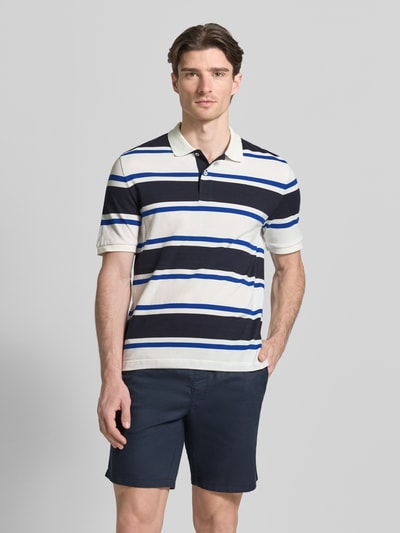 Männermodel trägt Slim Fit Poloshirt mit Logo-Stitching von Gant, weiße und blaue Streifen, Bio-Baumwolle, Ganzkörperansicht von vorne.