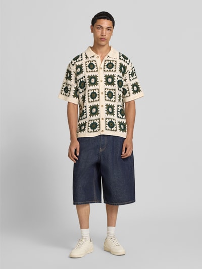 Männermodel trägt Regular Fit Freizeithemd im Allover-Look Modell 'FABIAN' von Redefined Rebel mit Polokragen und Knopfleiste, Ganzkörperansicht von vorne. Rückenlänge bei Größe M: 70 cm, Schulterbreite bei Größe M: 43 cm, Ärmellänge bei Größe M: 28 cm. Farbige Häkeloptik mit geometrischem Muster und strukturierter Textur.