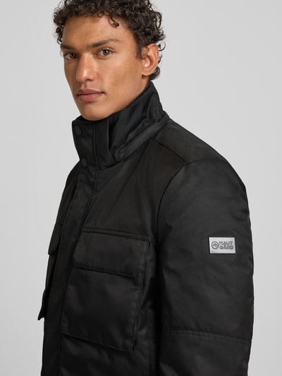 Männermodel trägt Jacke mit Pattentaschen Modell von NAUTGÅRD, Regular Fit, Kapuze, schwarze Farbe, Nahaufnahme Oberkörper. Rückenlänge bei Größe M: 96 cm, Schulterbreite: 46 cm, Brustweite: 59 cm, Ärmellänge: 71 cm.