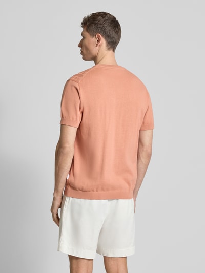Männermodel trägt T-Shirt mit Zopfmuster von Lindbergh in Strick-Optik, reine Baumwolle, Pfirsichfarbe, Ganzkörperansicht Rückansicht.
