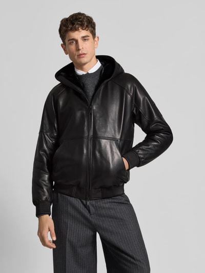 Männermodel trägt Jacke in Leder-Optik von Moose Knuckles in Schwarz mit Zweiwege-Reißverschluss und Känguru-Tasche, Ganzkörperansicht von vorne. Rückenlänge 69 cm, Schulterbreite 43 cm, Ärmellänge 67 cm.