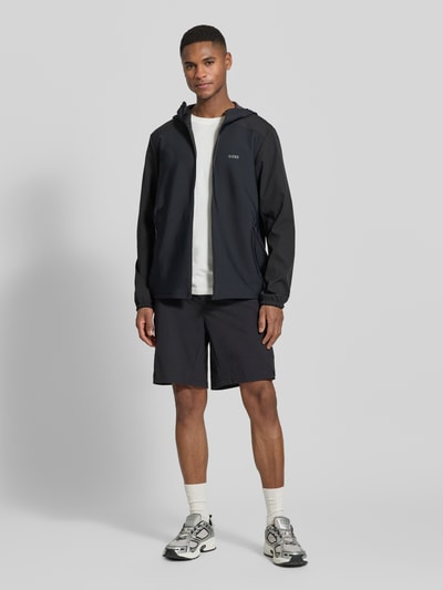 Männermodel trägt Regular Fit Softshell-Jacke mit Kapuze Modell 'LW_CRUISLITE' von BOSS Green in Unifarbe, Ganzkörperansicht von vorne.