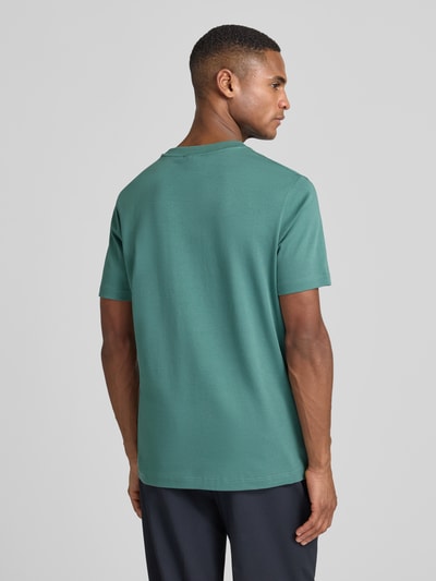 Männermodel trägt T-Shirt mit Label-Stitching Modell 'Priamo' von JOOP! Collection in Grün, reine Baumwolle, Rückansicht, Ganzkörperansicht.