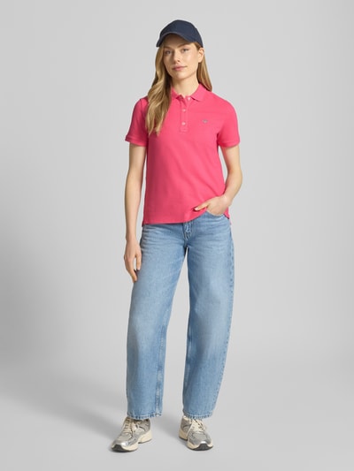 Frauenmodel trägt Poloshirt mit Logo-Stitching und Polokragen von Gant in Pink, Reine Baumwolle, Regular-Fit, Rückenlänge 57 cm, Ganzkörperansicht von vorne.