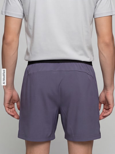 Männermodel trägt graue Regular Fit Sportshorts mit Logo-Print Modell 'M PWRMODE 5' von PUMA, Herren Sportshorts, Ganzkörperansicht Rückansicht.