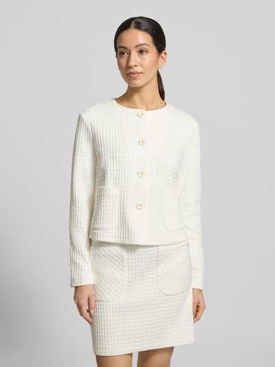 Frauenmodel trägt Blazer mit Rundhalsausschnitt von Marc Cain aus cremefarbenem Baumwoll-Mix mit Struktur, Knopfleiste, Eingrifftaschen, Regular Fit, Nahaufnahme Oberkörper.