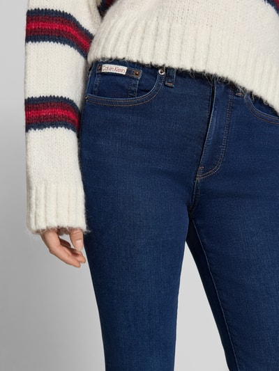 Kobiece modelka nosi Skinny Fit Jeans mit 5-Pocket-Design od Calvin Klein Jeans, ciemnoniebieski jeans, detal z logo, zbliżenie na biodra, zdjęcie z przodu.