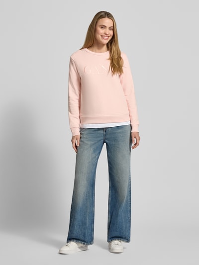 Frauenmodel trägt Sweatshirt mit Label-Stitching und Rundhalsausschnitt von Gant in Rosa aus reiner Baumwolle, locker geschnitten, Ganzkörperansicht von vorne.