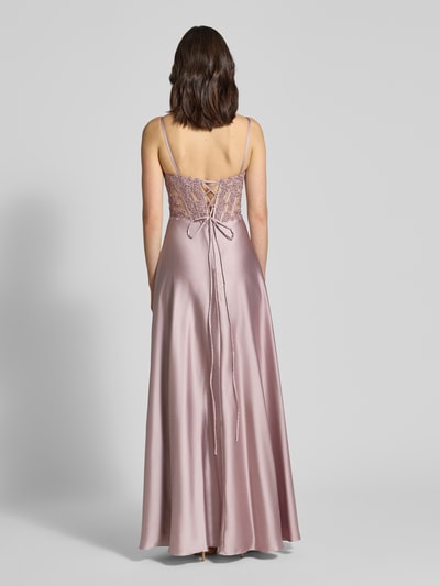 Frauenmodel trägt Abendkleid mit floralem Spitzenbesatz von Mascara in zartem Rosaton aus Satin mit Rückenschnürung, Maxilänge, Ganzkörperansicht Rückansicht. Kontext: Damen Abendkleid, taillierte Passform, Spaghettiträger, Herz-Ausschnitt, floraler Spitzenbesatz mit Ziersteinen, semitransparentes Design, Nahtreißverschluss, Maxilänge, Satin-Rockteil, Rückenlänge Größe 36: 154 cm, Brustweite 41 cm.