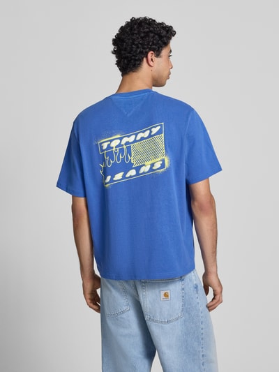 Männermodel trägt Regular Fit T-Shirt aus reiner Baumwolle Modell '90s' von Tommy Jeans, Optik: Unifarben, Label-Print, Ganzkörperansicht Rückansicht