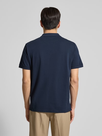 Męski model nosi Regular Fit Poloshirt aus reiner Baumwolle od Tom Tailor, granatowy kolor, jednolity, pikowana bawełna, widok całej sylwetki od tyłu.