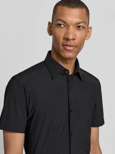 Männermodel trägt Slim Fit Businesshemd mit kurzem Arm Modell 'P-HANK-K-SH-262' von BOSS in Schwarz mit Kentkragen, Nahaufnahme Oberkörper.