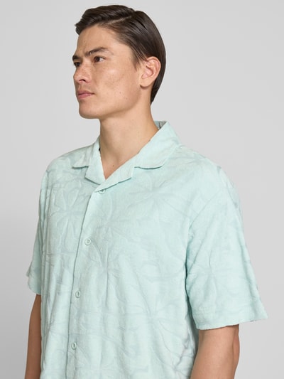 Männermodel trägt Regular Fit Freizeithemd aus Baumwoll-Mix Modell 'WE_FLOWER' von BOSS Orange in Hellgrün mit Strukturmuster, Nahaufnahme Oberkörper.
