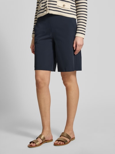 Kobiece model prezentuje Schlupfbermuda Techno Cotton Superstretch od Raffaello Rossi, krój regular fit, elastyczny pas, kieszenie tylne, szerokość w rozmiarze 36: 39 cm, długość nogawki wewnętrznej w rozmiarze 36: 24 cm, ciemnoniebieski kolor, gładka tkanina, widok całej sylwetki z przodu.