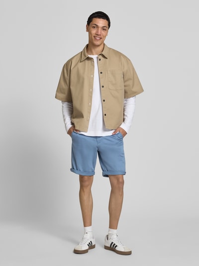 Męski model nosi Regular Fit Shorts mit Eingrifftaschen Modell 'BOWIE' od Jack & Jones, mieszanka bawełny i elastanu, kolor jasnoniebieski; krój regular fit, wpuszczane kieszenie, brzeg, szerokość w rozmiarze M: 43 cm, długość wewnętrzna nogawki w rozmiarze M: 26 cm, widok całej sylwetki z przodu.