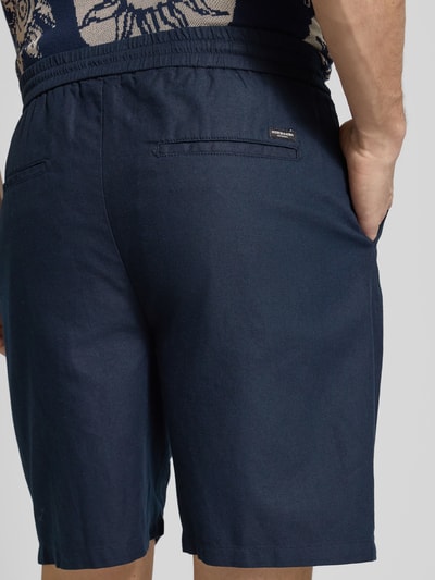 Männermodel trägt Shorts aus Baumwoll-Leinen-Mix Modell 'FAVE' von Scotch & Soda in Dunkelblau, Regular Fit, elastischer Bund, Detailaufnahme Rückansicht.