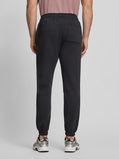 Männermodel trägt Sweatpants mit Logo und elastischem Bund von GAP, schwarze Farbe, Baumwoll-Mix, Regular-Fit, Ganzkörperansicht Rückansicht.