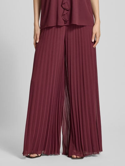 Frauenmodel trägt Hose aus Chiffon mit Plisseefalten von V by Vera Mont in Dunkelrot, Wide Leg, Elastischer Bund, Nahaufnahme Unterkörper, Bundweite bei Größe 36: 39 cm, Innenbeinlänge bei Größe 36: 81 cm.