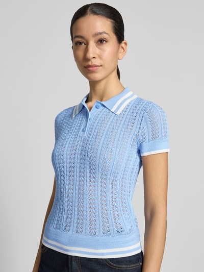 Modelka nosi Strickshirt aus Viskose-Mix mit Polokragen von Guess, mieszanka wiskozy, krój slim fit, kołnierzyk polo, listwa guzikowa, paski w kontrastowym kolorze, długość tyłu w rozmiarze S: 51 cm, długość rękawów w rozmiarze S: 13 cm, błękit i biel, ażurowa dzianina, widok przód górnej części sylwetki.