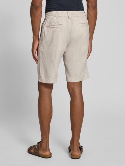 Mannenmodel draagt Tapered Chinoshorts uit linnenmix model 'DS_3S' van BOSS Orange, zandkleur, met boord, tunnelkoord, riemlussen, labelpatch, steekzakken, paspelzakken, materiaalverwerking: gevlamd garen, pasvorm: tapered fit, model: achteraanzicht volledige lichaamsfoto.